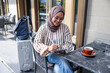 © Jovo Jovanovic/Stocksy - Woman in hijab works on tablet at outdoor cafe.
