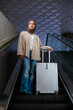 © Jovo Jovanovic/Stocksy - Woman in hijab with suitcase on escalator.