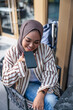© Jovo Jovanovic/Stocksy - Young woman using voice command on smartphone at outdoor cafe