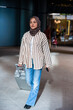 © Jovo Jovanovic/Stocksy - Woman in hijab pulls suitcase in modern building.