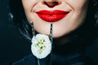 © VICHIZH - Elegant woman with red lipstick holding sushi with chopsticks on dark background, showcasing a minimalist and modern culinary concept.