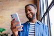 © BONNINSTUDIO/Stocksy - Man smiling, enjoying mobile phone content at office
