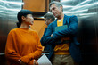 © Artcore Studio/Stocksy - Business colleagues having serious conversation in modern elevator