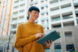 © Artcore Studio/Stocksy - Asian woman using tablet outdoors in urban setting