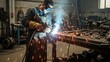 © hilwanstock - A man in a welding mask and protective gear welding a piece of metal in a workshop with sparks