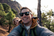 © Santi Nuñez/Stocksy - Father and son taking a selfie while hiking