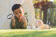 © Kunlathida - An Asian little boy is playing in his teepee in the garden, have fun playing with a magnifying glass