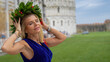 © jovannig - Elegant graduate walking under the Leaning Tower of Pisa wearing a laurel wreath in Piazzale dei Miracoli