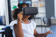 © Wavebreak Media - African American girl sitting at desk in classroom wearing virtual reality headset holding front