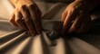 © Ilham - In a soft, intimate glow, a person's hands delicately adjust or caress smooth grey fabric, evoking moments of comfort, reflection, and quiet anticipation within a tranquil, personal space