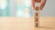 © Gayan - Caucasian adult hand stacking wooden blocks with ladder icons and gear symbols on a table, symbolizing career growth, business progress, and efficiency in a bright indoor setting.
