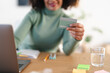 © Studio Marmellata - A person holds a credit card while using a laptop, ready to make an online purchase.