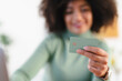 © Studio Marmellata - A person holds a payment card, ready to make a transaction. The card is green with a chip and embossed text.