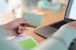 © Studio Marmellata - A person holds a payment card near a laptop, ready to make an online transaction.