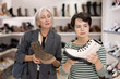© JackF - Two women are shopping in shoe store and young colleague shows elderly lady advantages of thick sole in modern winter boots