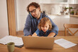 © Stockphotodirectors - A father balances work and family by taking a phone call while helping his young daughter at the kitchen table. They enjoy their time together as she interacts with him.