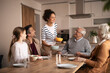 © Jelena - Multigenerational family gathering enjoying common meal at dinner table