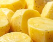 © volilah - Macro shot displaying freshly cut, peeled pieces of starchy root vegetables, with water droplets glistening on their smooth, pale yellow surfaces