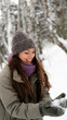 © ekaterinabyuksel - A beautiful young woman in winter clothes is happily spending her free time in a snowy forest. She enjoys the first snow. Active winter recreation.