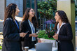© somchaikhun - Three businesswomen talking and drinking coffee outdoors, showcasing teamwork, communication, and professional collaboration in a modern corporate environment. Ideal for business, leadership, and work