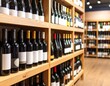 © Mah - A perspective shot showcases bottles on wooden shelves in a shop. Rows display varied shapes, sizes, and label designs. The setting is a retail environment