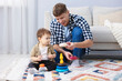 © New Africa - Smiling male nanny and cute little boy playing with toys on floor at home