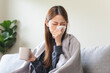 © Pormezz - Sick at home concept. Woman sneezing on the sofa in winter season.