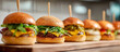 © Swan - Row of gourmet beef cheeseburgers with sesame buns on a rustic wooden board