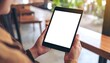 © deni - Mockup image of a woman holding digital tablet with blank white desktop screen in cafe