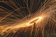 © Travel 'n' Lifestyle - View of sparks of light dance in the dark, painting fiery circles above the grassy ground with a silhouette of a person, Isle of Skye, United Kingdom.