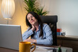 © Nenad - Tired business woman with neck pain looking uncomfortable while working with computer in the office.