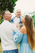 © DSMT - Family enjoys time together outdoors with child in a green setting during a sunny day in the afternoon