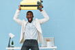 © SHOTPRIME STUDIO - Full body cheerful young black man in white blazer and shirt holding yellow suitcase overhead looking excited joyfully standing indoors against a pastel blue background. People lifestyle concept