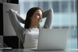 © fizkes - End of day relaxation. Portrait calm peaceful young woman employee lean back on office chair with hands behind head enjoy successful finishing work look aside from notebook screen with serene smile