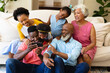 © wavebreak3 - African american three generation family using smartphone sitting together on the couch at home