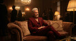 © i-element - Elegant mature man in a luxury burgundy suit sitting on a velvet sofa with a glass of whiskey at a party
