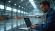 © Vadym - Man works on laptop inside airplane hangar. Technician types on computer near aircraft. Aviation mechanic uses tech for service. Pro checks data for plane. Industry worker does job.
