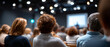 © perfectlab - Audience attending a conference or seminar in a modern auditorium with focus on people listening to a speaker on stage