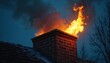 © Maryna - A chimney is on fire at night. Flames erupt from brick smokestack atop the roof. Thick black smoke rises against the dark sky. Fire safety warning emergency situation home hazard