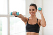 © Prostock-studio - Home Sports During Covid Lockdown. Young woman doing fitness exercises with weights indoors, holding and using dumbbells. Happy lady strengthening her arm muscles, leading healthy lifestyle