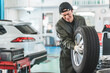 © buritora - Male mechanic carrying tires at an auto repair shop (physical labor, hard work, heavy, back pain)