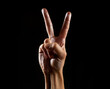 © Volodymyr - Hand peace gesture on black background. Hand signaling victory with two fingers raised. Hand V gesture. Hand peace and victory concept.