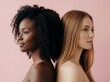 © Meow Creations - Side profile of diverse african and caucasian women standing back to back isolated on pink background