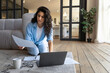 © Prostock-studio - Focused young female freelancer working online, looking through financial documents, using laptop indoors, copy space. Millennial woman having remote business meeting at home office