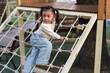 © geargodz - happy child girl playing with climbing ropes net at outdoor playground