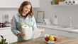 © Pixel-Shot - Young woman with roll of paper towels and apples near table in kitchen