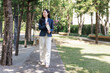 © crizzystudio - Young businesswoman walking outdoors carrying tablet smiling