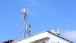 © kanin - Cell tower on the roof of a building. Macro base station or base transmitter, telecommunications station with antennas of 4G and 5G cellular against blue background. Selective focus