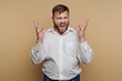 © bodnarphoto - Man shows frustration while yelling with hands raised in a studio against a beige background