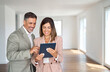 © insta_photos - Bank consultant or broker using digital tablet showing buyer investor new property investment offer for mortgage loan investing or buying real estate standing in new apartment, banner.